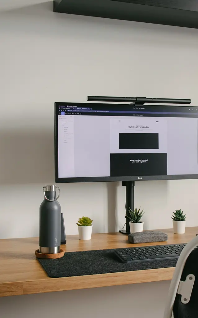 Desk with a monitor showing a website layout in progress, plants and a keyboard